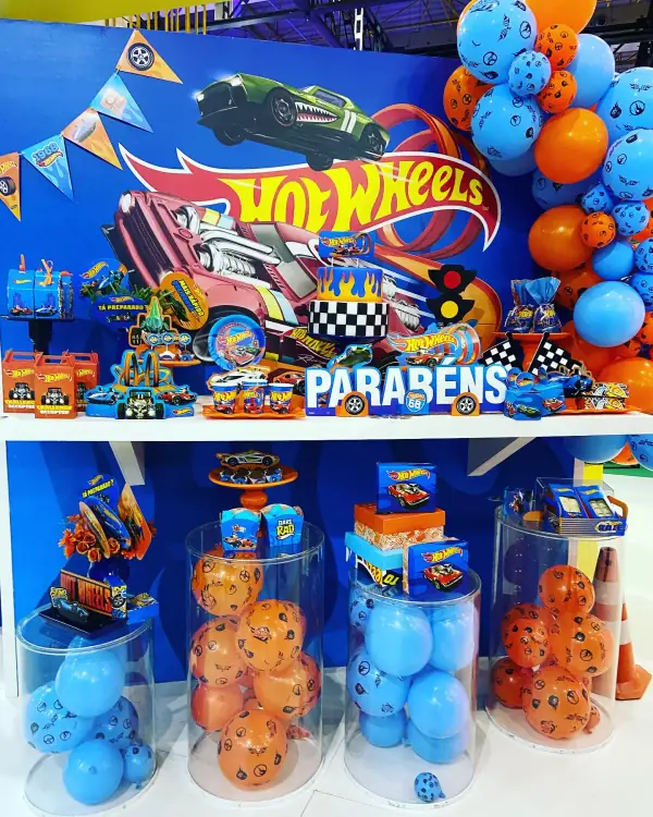 Mesa de festa montada com tema de carrinhos, com painel, balões e docinhos